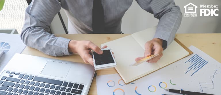 a desk covered with a laptop, bills and charts.